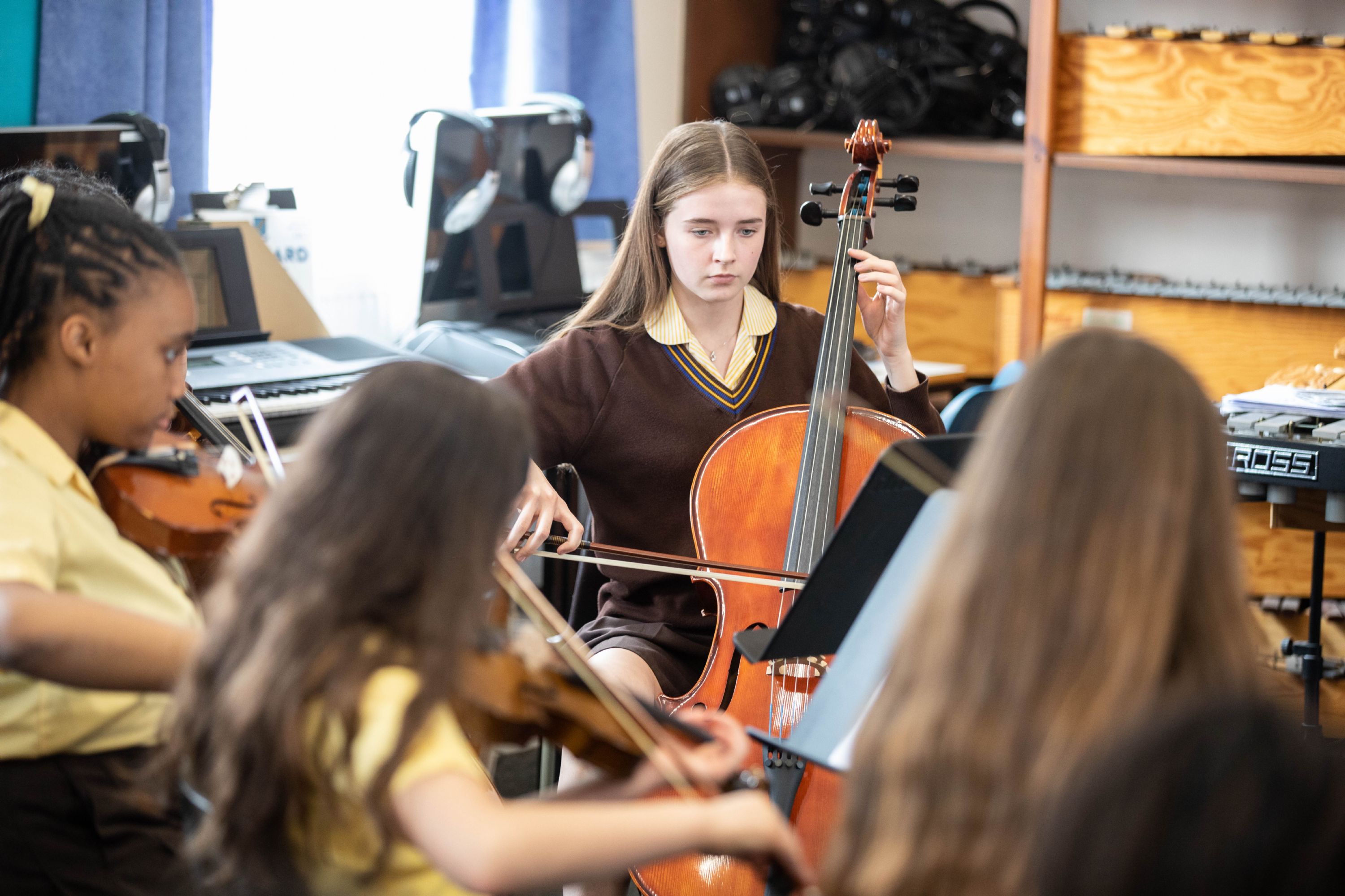 Students playing stringed instruments in a classroom